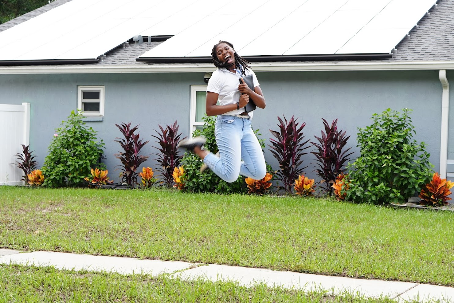 An image of a Zone 5 Representative jumping and smiling in front of a new solar installation. Is solar a scam?