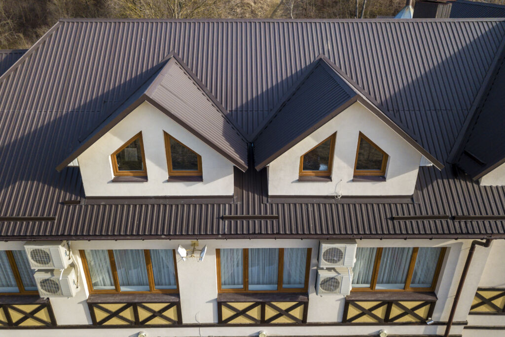 An aireal shot of a home with a beautiful metal roof. The roof has a satisfying auburn color to it. 