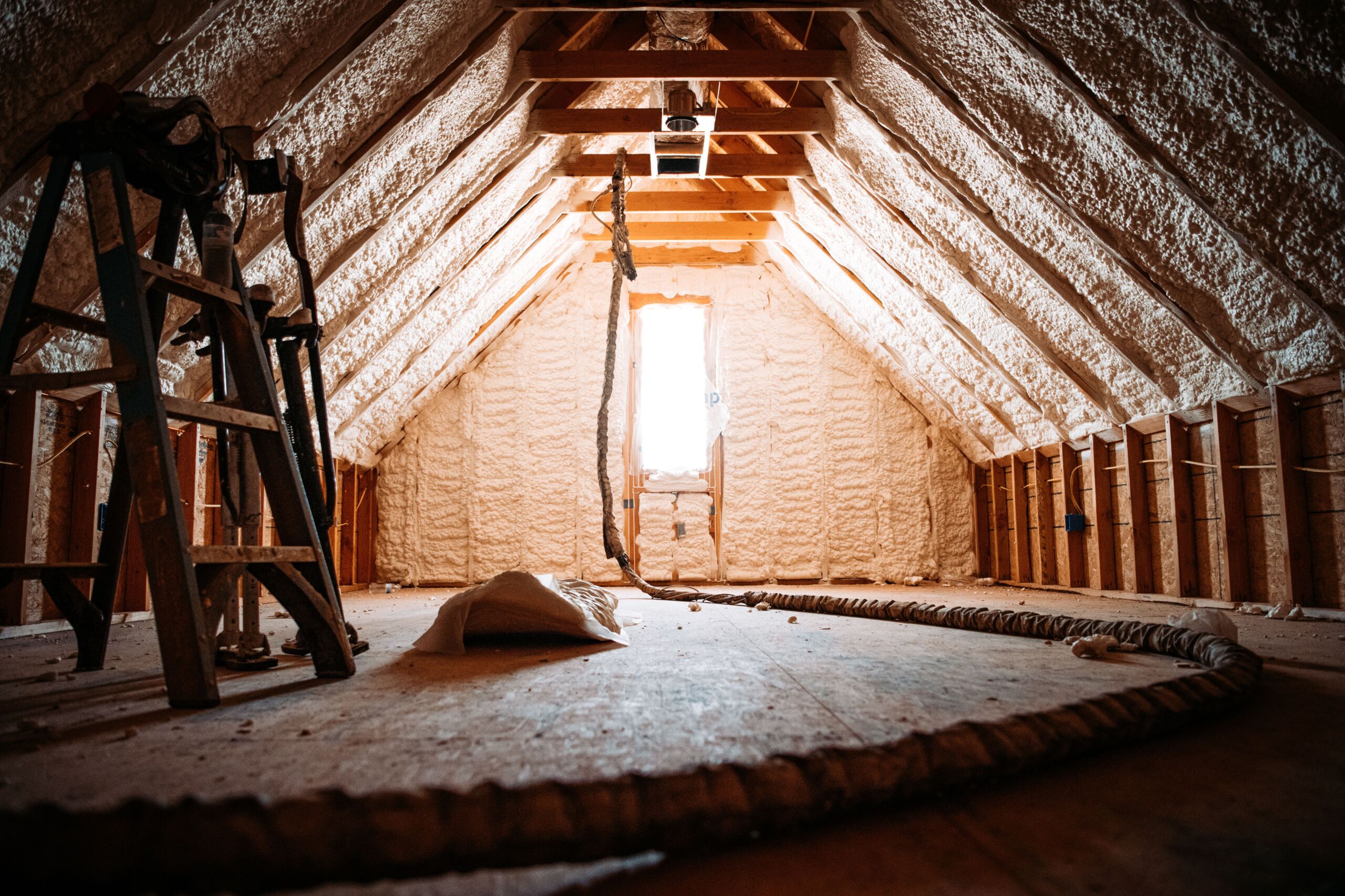 An image of spray foam insulation in an attic. The attic is cool, cost effective, and clear of pests. 